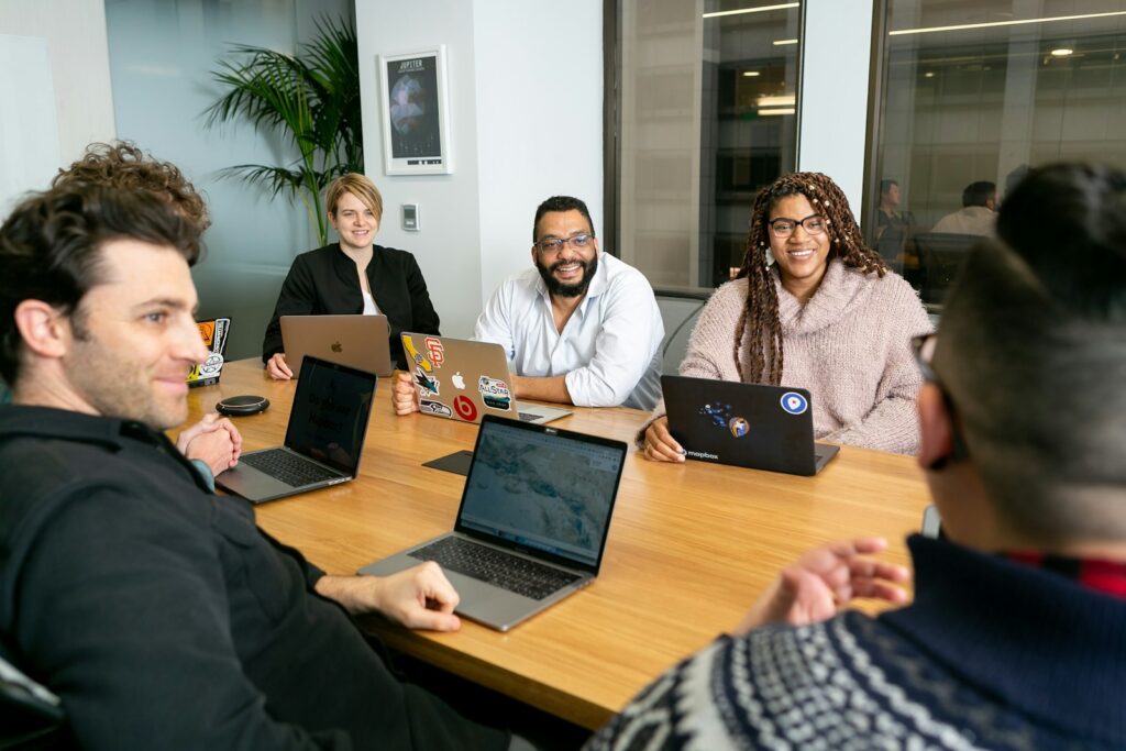 Team aus vier Personen mit Laptops bespricht im Meeting die Prioritäten für den nächsten Sprint