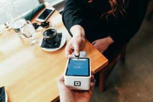 Verkäuferin hält eine mobile Kasse mit Kartenleser in der Hand