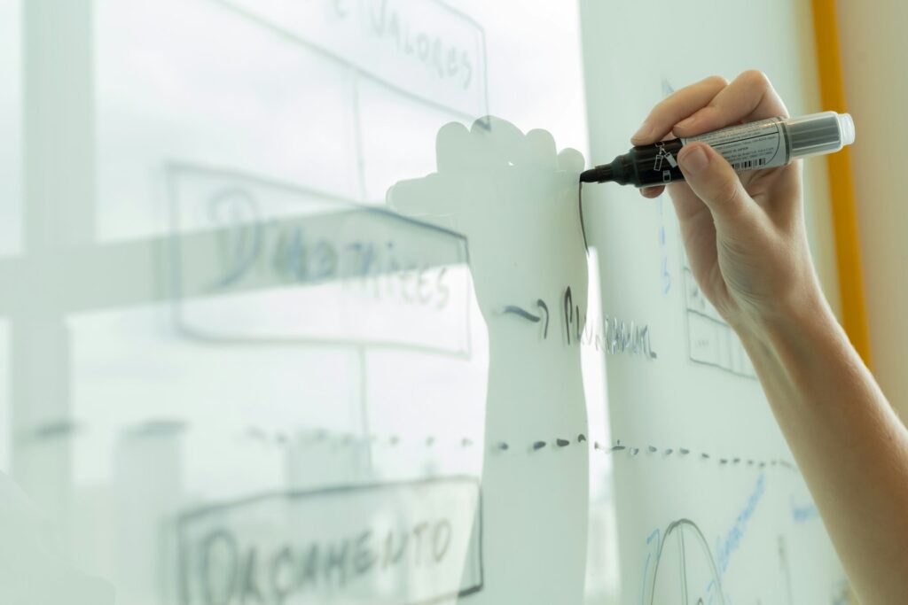Hand zeichnet ein Diagramm auf ein klassisches Whiteboard