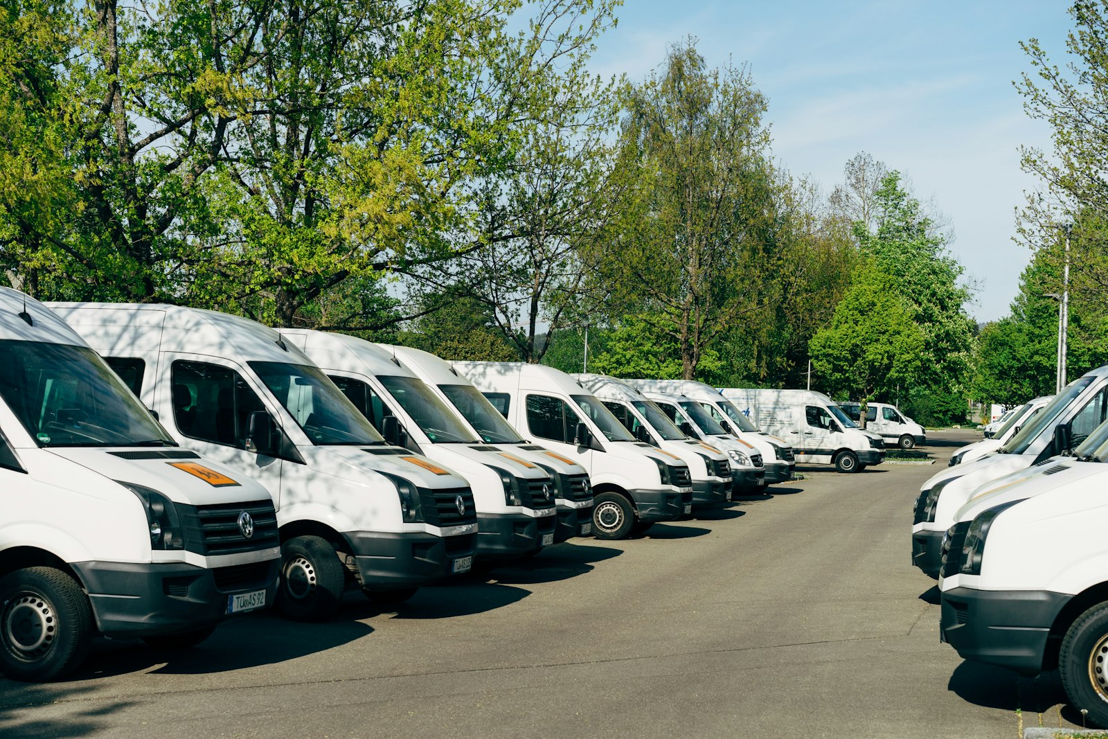 Reihe weißer Firmentransporter auf einem Parkplatz, deren Nutzung ein elektronisches Fahrtenbuch erfasst