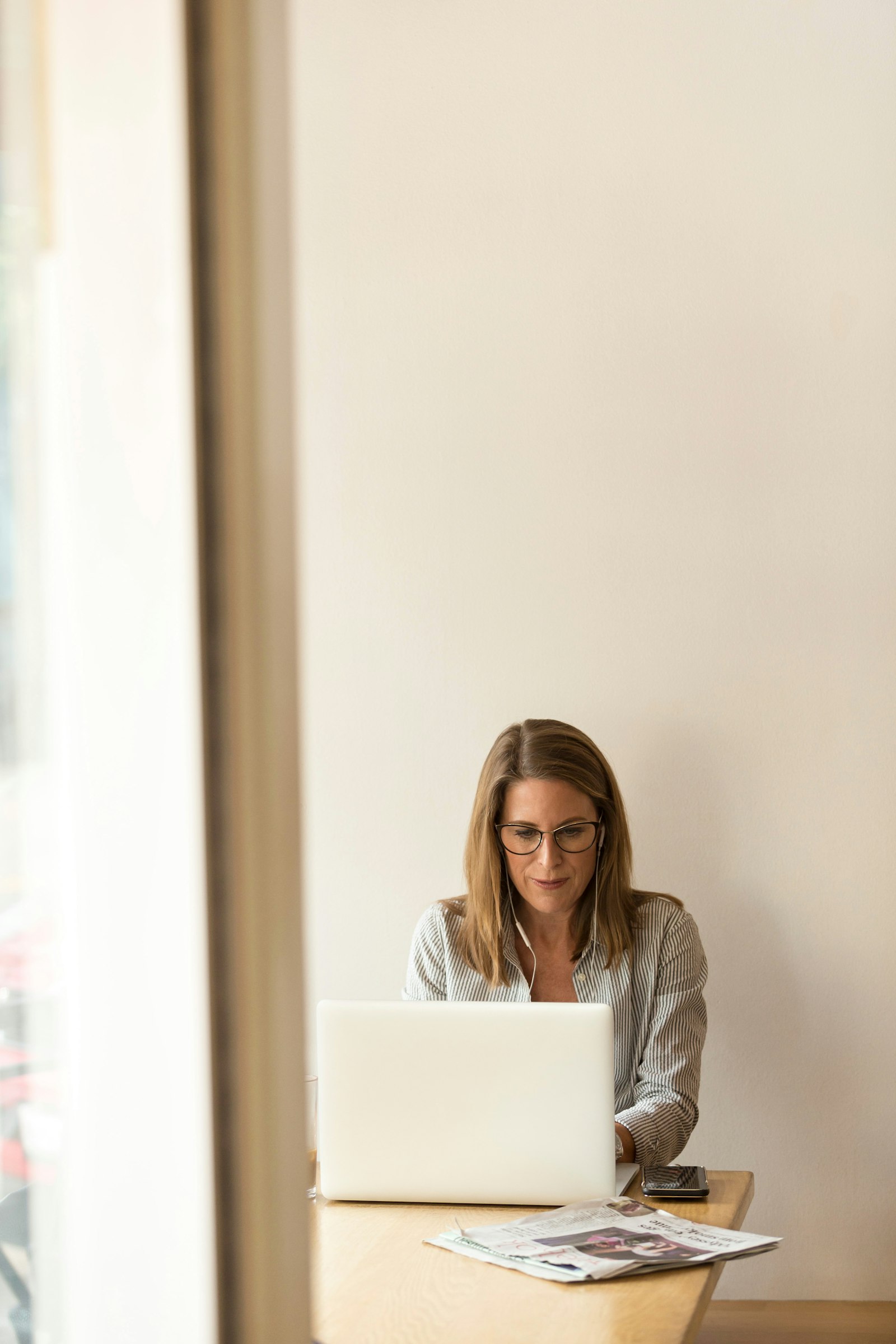 Gründerin arbeitet an einem Holztisch am Laptop und plant, welche Kompetenzen sie ausbauen will