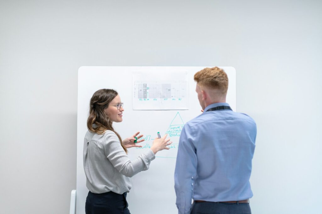 Zwei Kolleginnen besprechen Ideen an einem Whiteboard – Führungskompetenz im Startup-Alltag