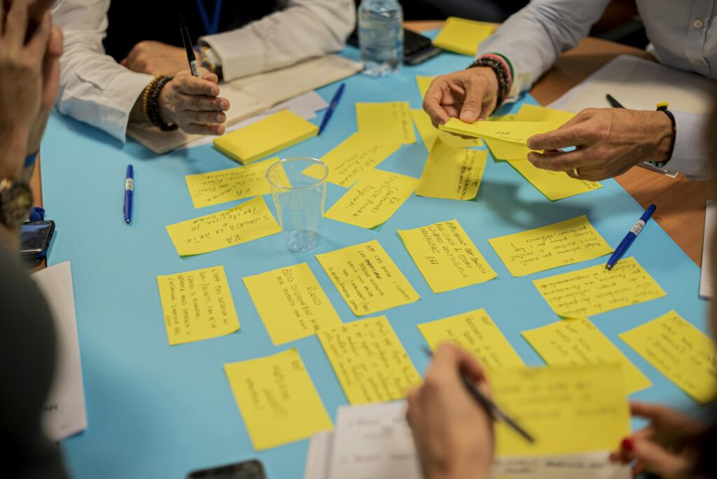 Hand klebt gelbe Haftnotizen an eine Wand – Wachstumsideen im Team sammeln und sortieren