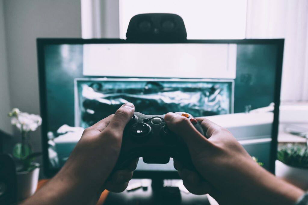 Person hält einen Gamecontroller vor einem Fernseher – Cloud Gaming auf dem Smart-TV