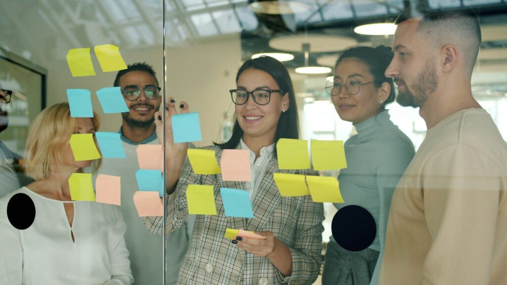 Team skizziert Arbeitsabläufe mit Haftnotizen an einer Glaswand als Vorbereitung für die Digitalisierung
