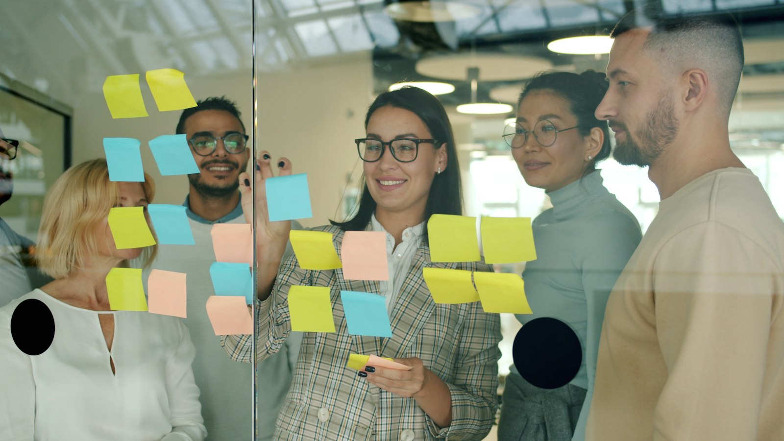 Team skizziert Arbeitsabläufe mit Haftnotizen an einer Glaswand als Vorbereitung für die Digitalisierung