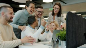 Startup-Team feiert gemeinsam am Schreibtisch einen Erfolg als Teil einer guten Employee Experience