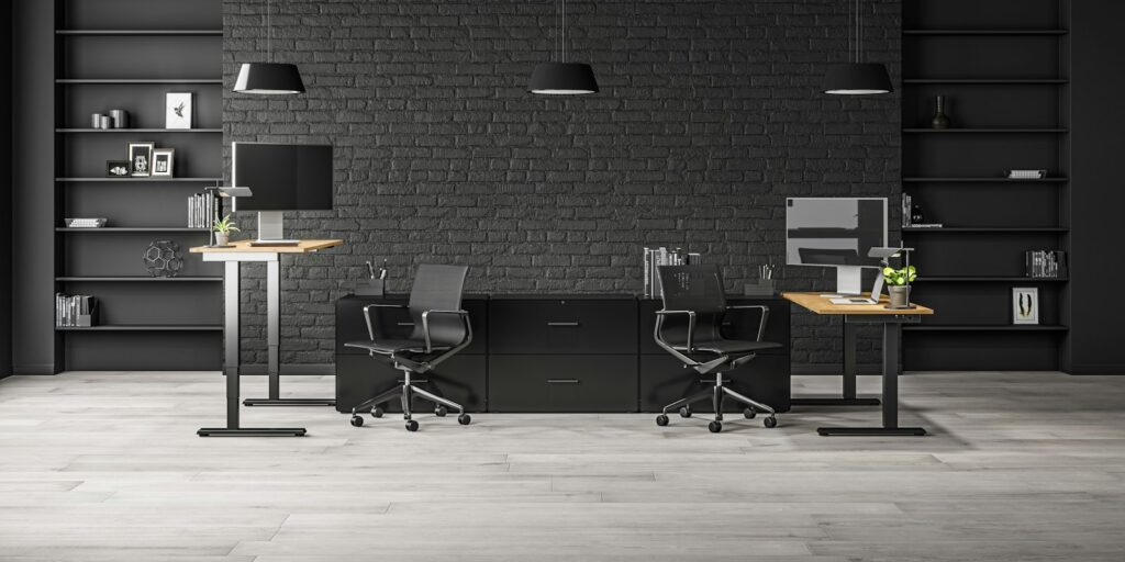 Zwei Arbeitsplätze mit Monitoren vor einer dunklen Backsteinwand in einem Smart Office