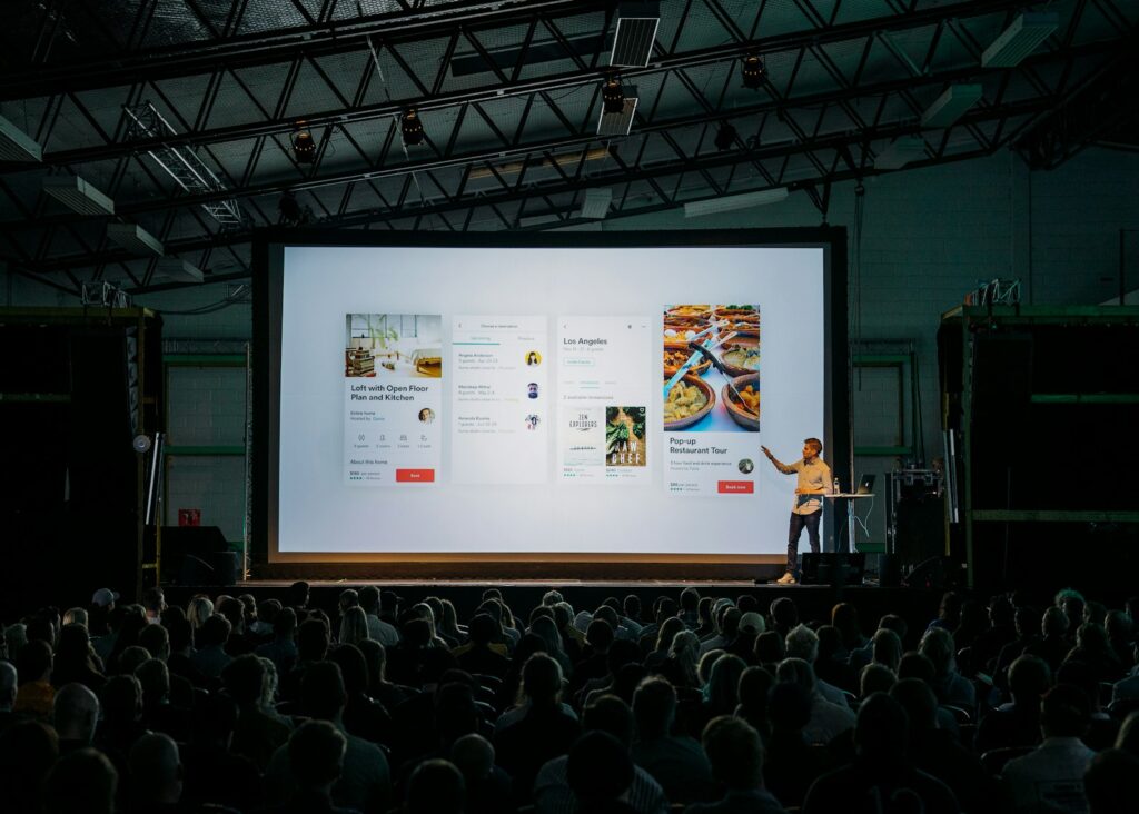 Gründerin präsentiert ihr Pitch Deck vor Publikum auf einer großen Leinwand
