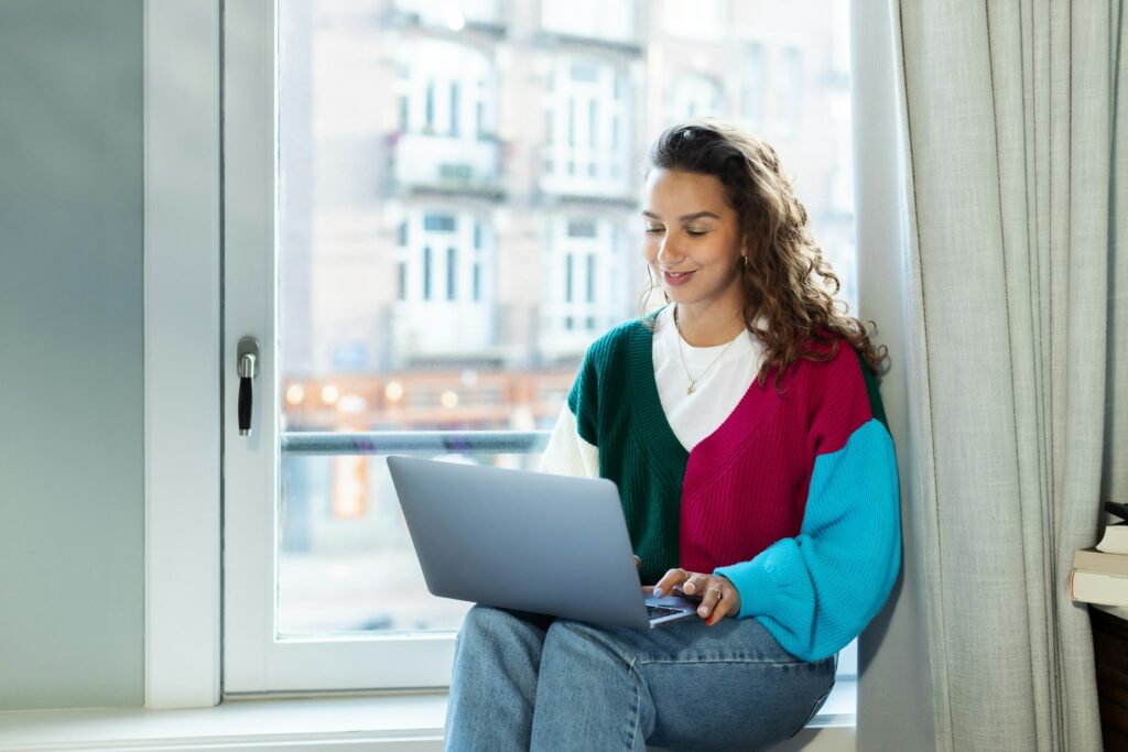 Freelancer arbeitet mit Laptop auf einer Fensterbank