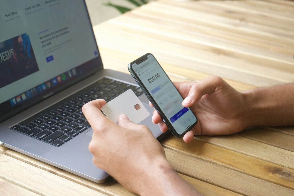 Person kauft online mit Smartphone und Laptop ein, beim Bezahlen kann künftig auch Wero eine Option sein
